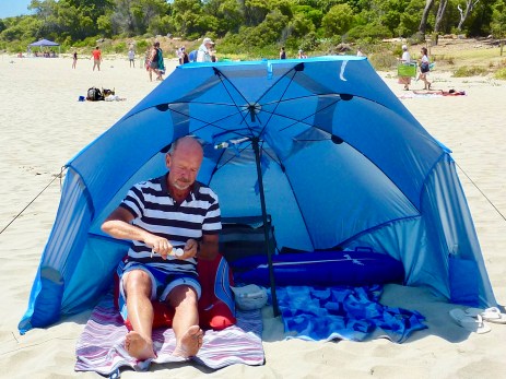Paul putting on sun screen under our own beach shelter.
